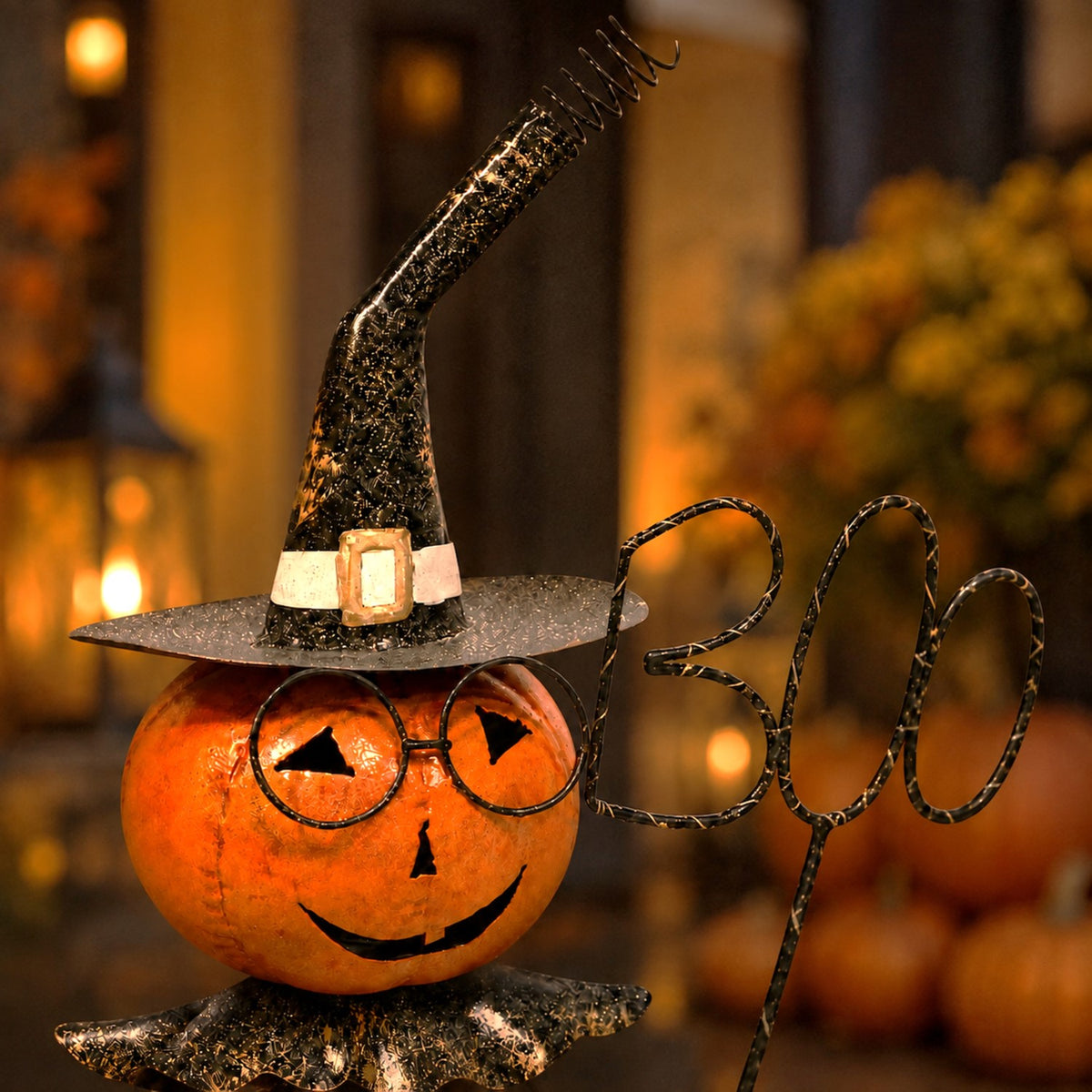 Close-up of the pumpkin face, pointed witch hat and wire sign against a softly lit background.