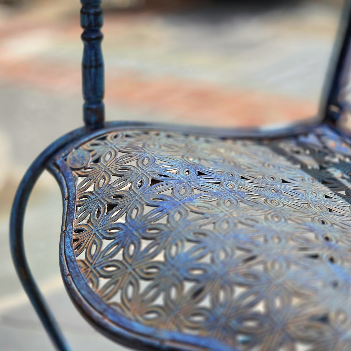 Close-up of the bench’s openwork metal seat with repeating leaf-shaped cutouts and a curved edge.