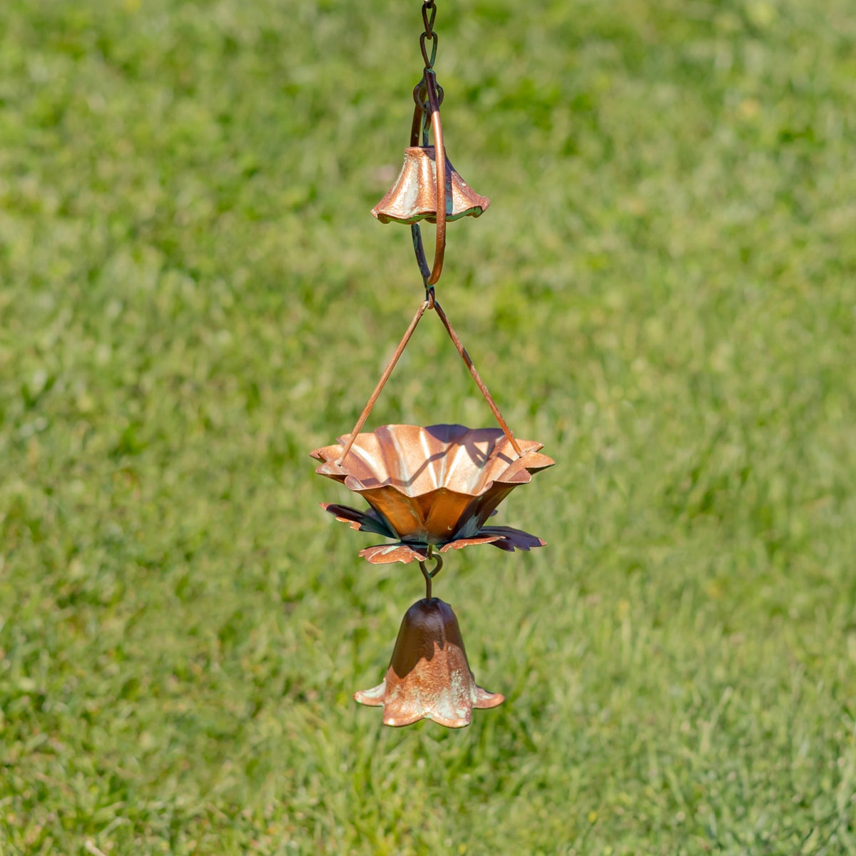 A small bell hangs beneath a copper-toned lotus cup, with another bell suspended above it.