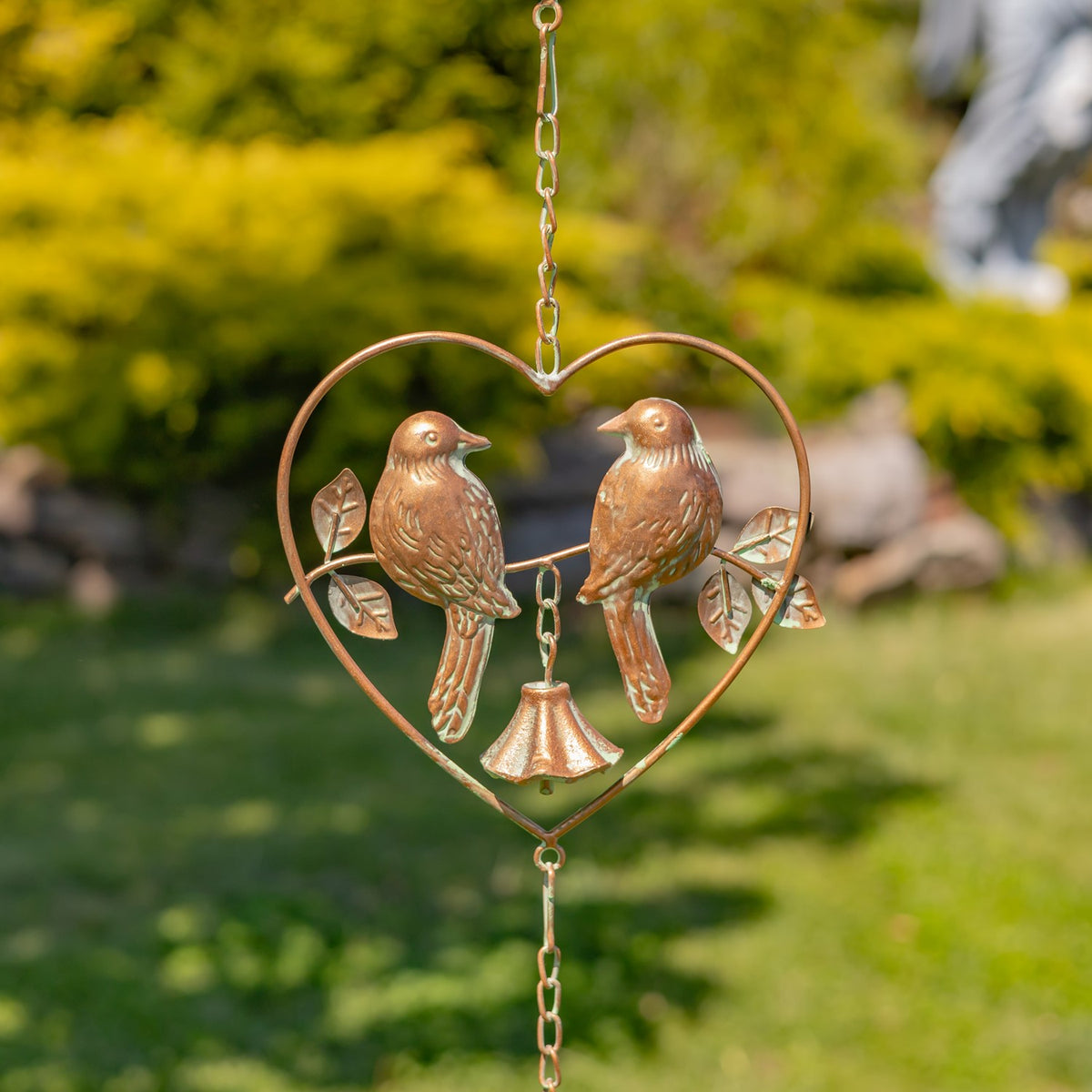 A single heart-shaped ornament shows two facing birds, leafy branches and a bell suspended between them.