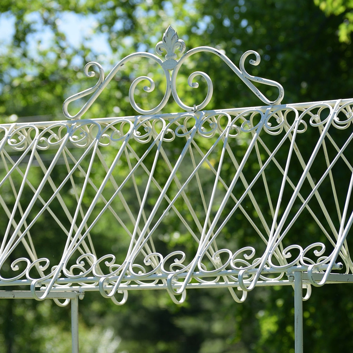 Close-up of the flower cart’s white scrollwork canopy against leafy trees.