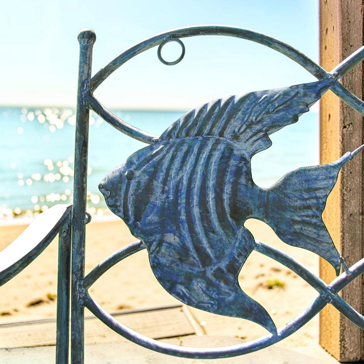 Close-up of a blue iron fish detail against a beach and ocean view