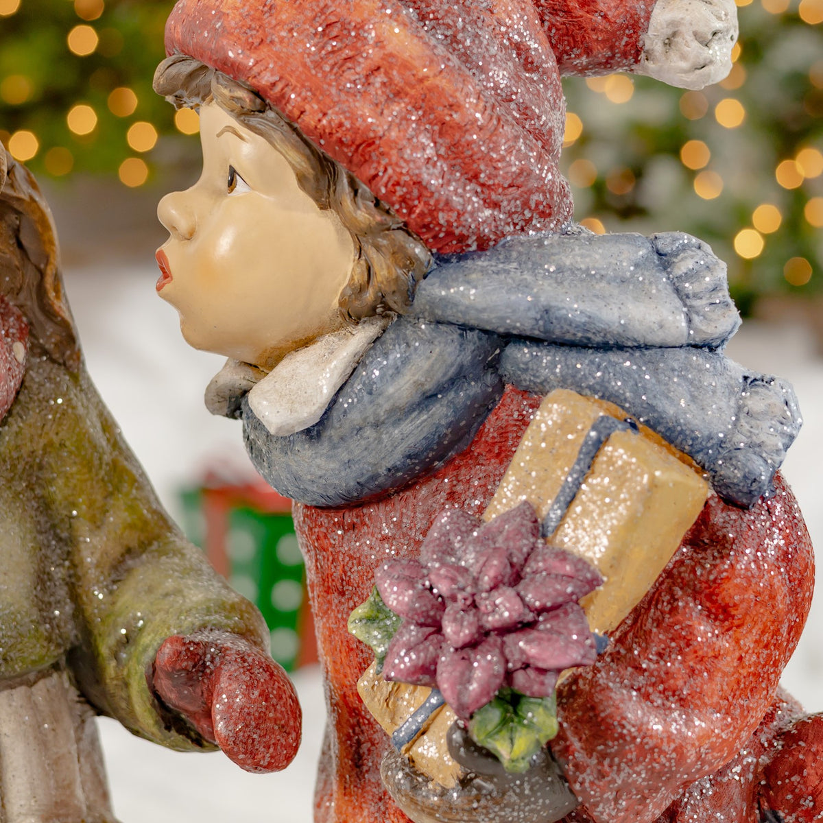 Boy figurine in red clothing holding a wrapped gift and flower