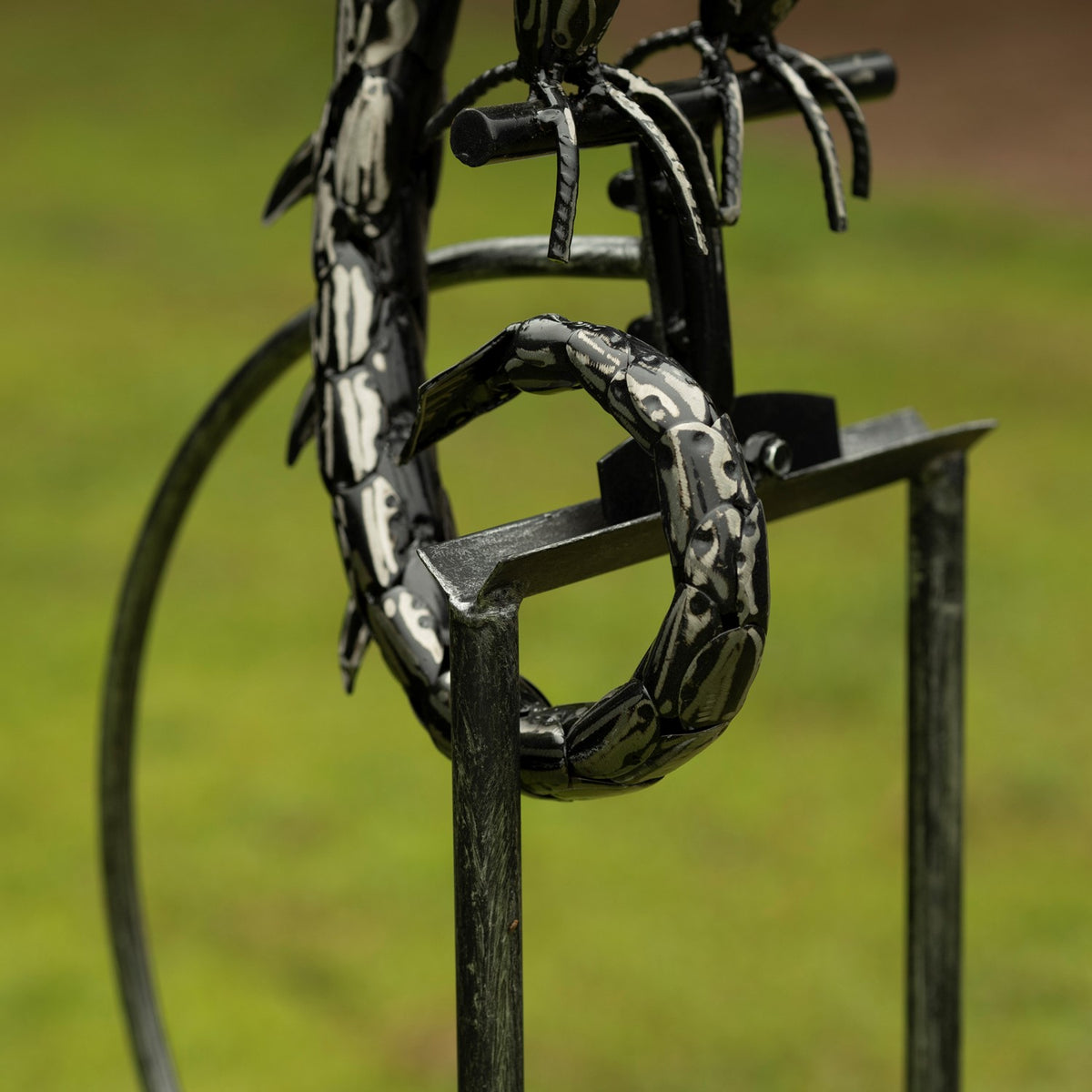 Close view of the dragon’s curled tail resting across the top of its metal stake frame.