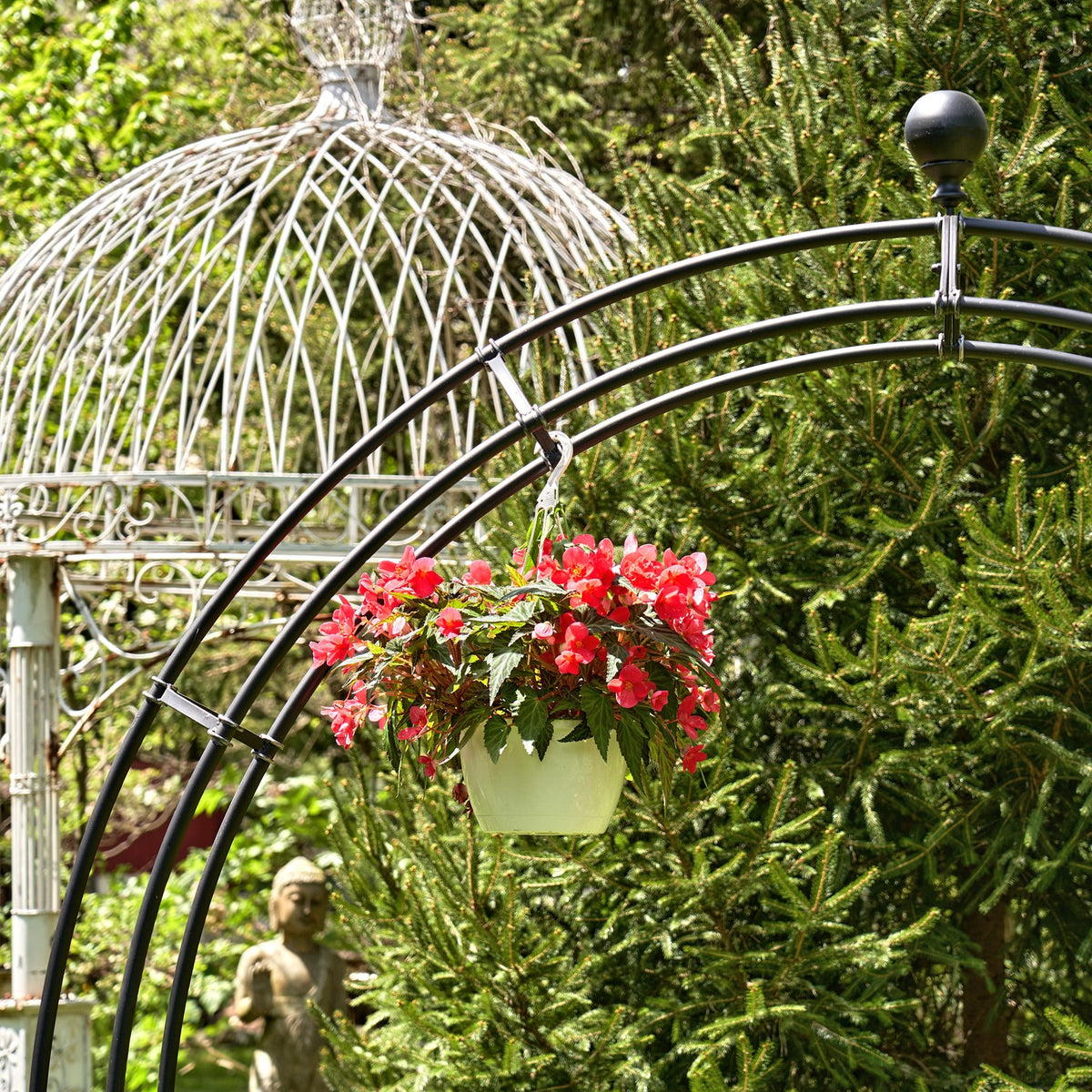 Close view of a flower basket hanging from the black curved garden arch