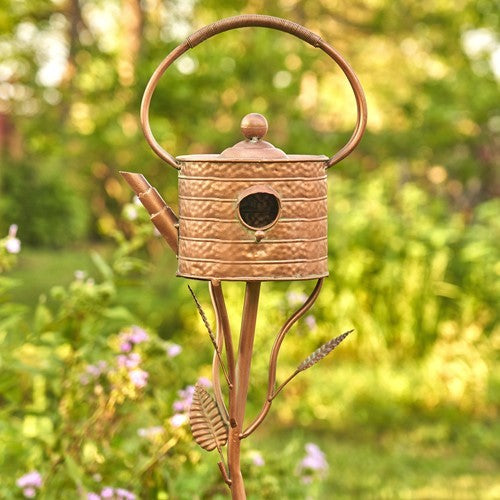 Front view of the copper teapot birdhouse and handle in a garden