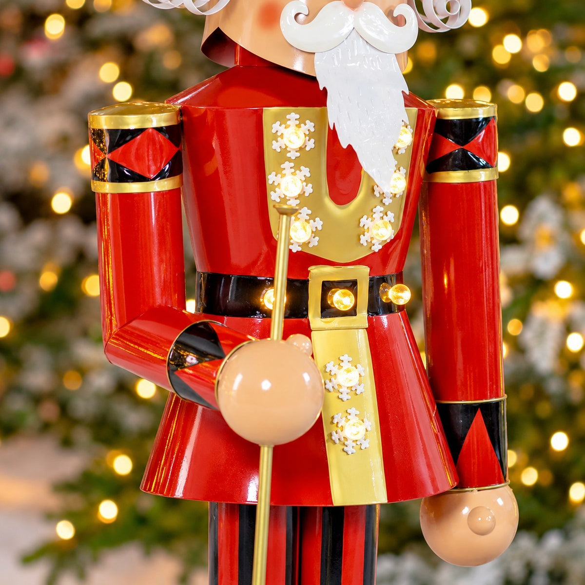 Close-up of a red-and-gold nutcracker holding a trumpet, with small lights glowing on its uniform.