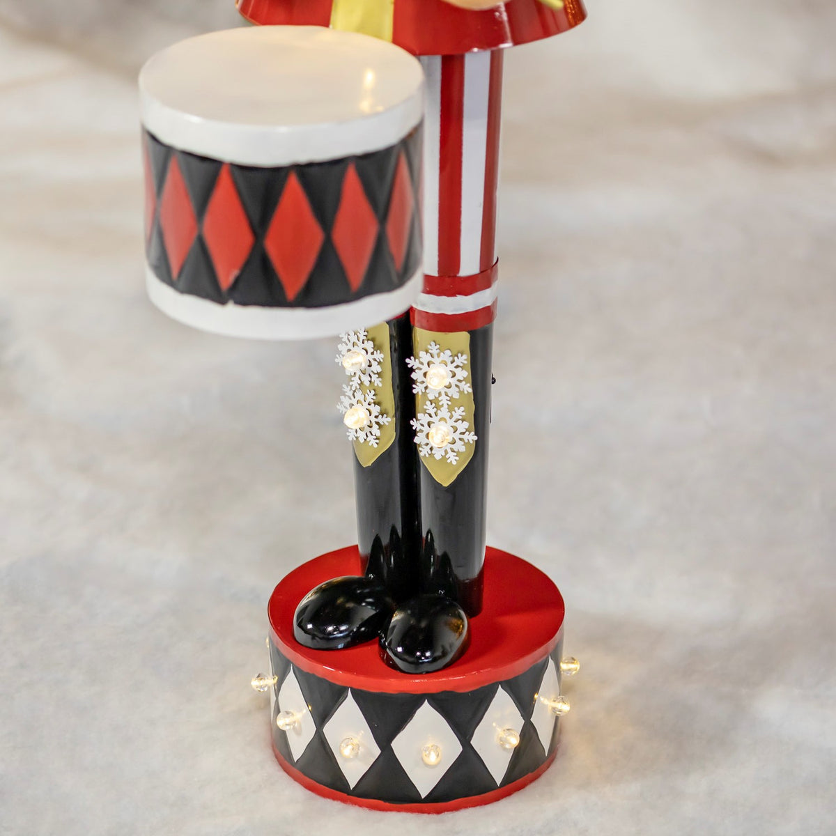 Close-up of the nutcracker’s patterned drum, black boots, and illuminated diamond-patterned base.