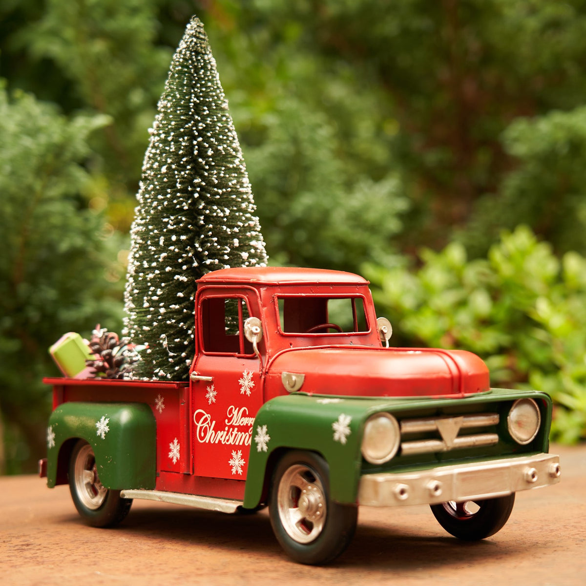 Front three-quarter view of a red and green holiday truck with a miniature tree