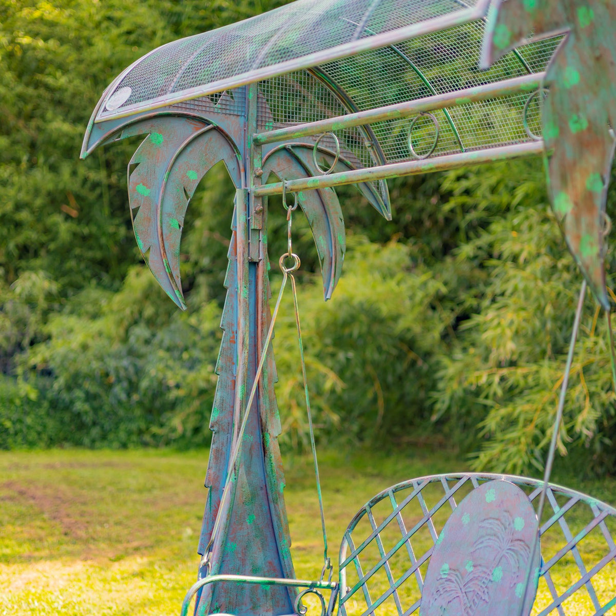 Detail of the swing chains and palm-tree support, with part of the bench visible