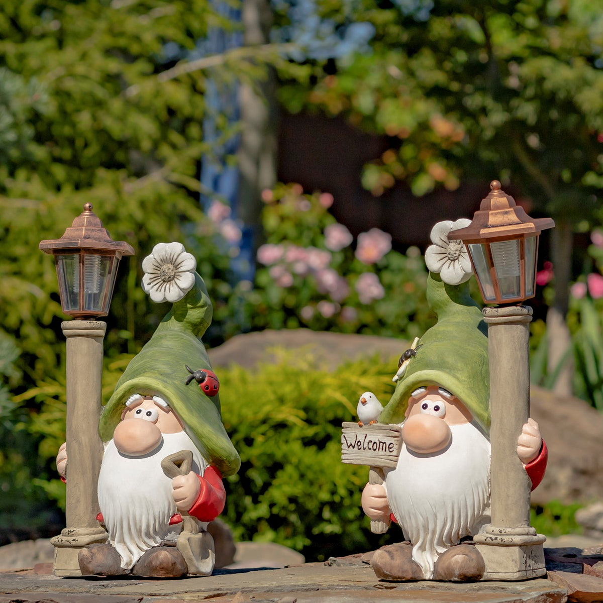 Pair of garden gnomes and lanterns displayed among greenery and flowers