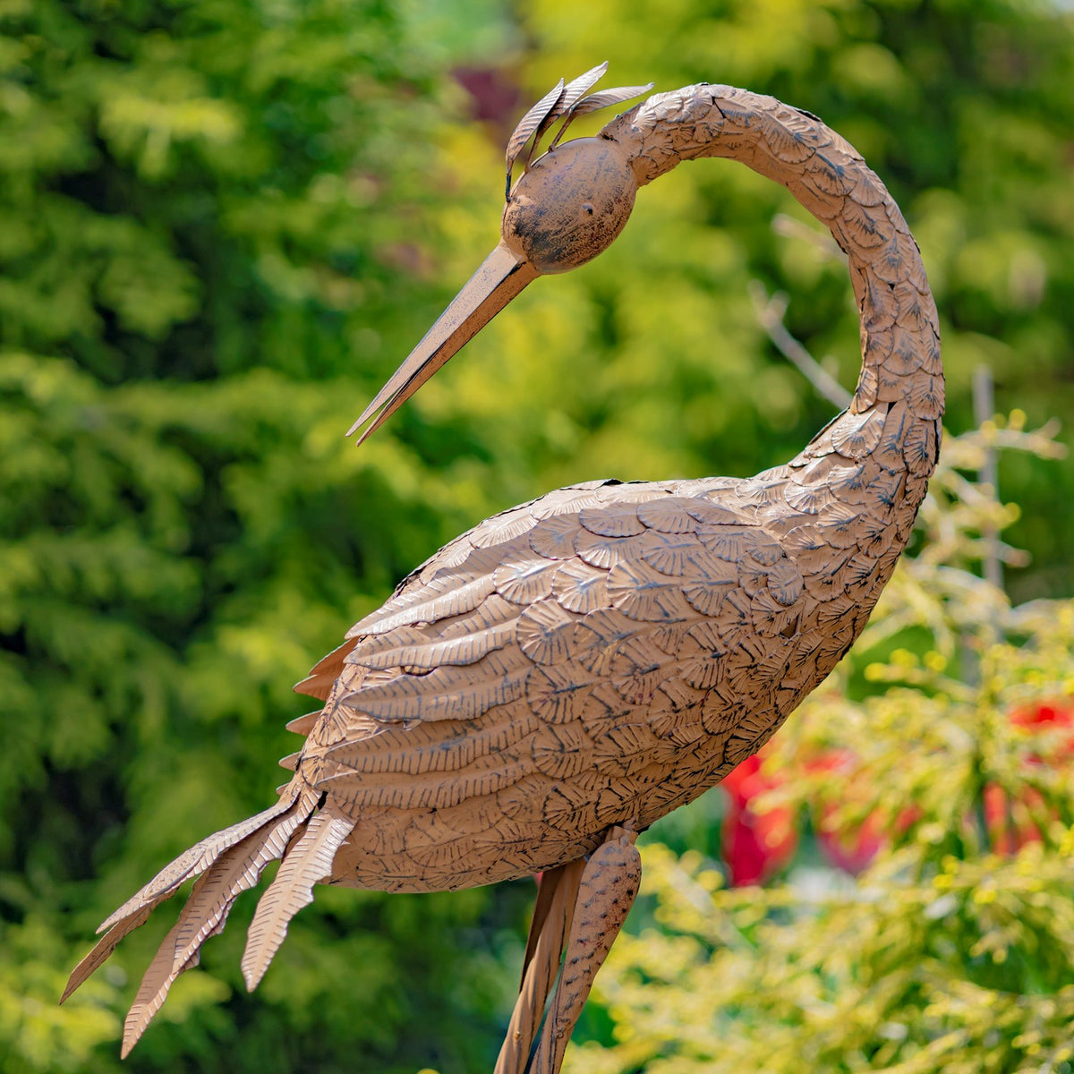 Close-up of one rust-finish crane sculpture showing layered feather details