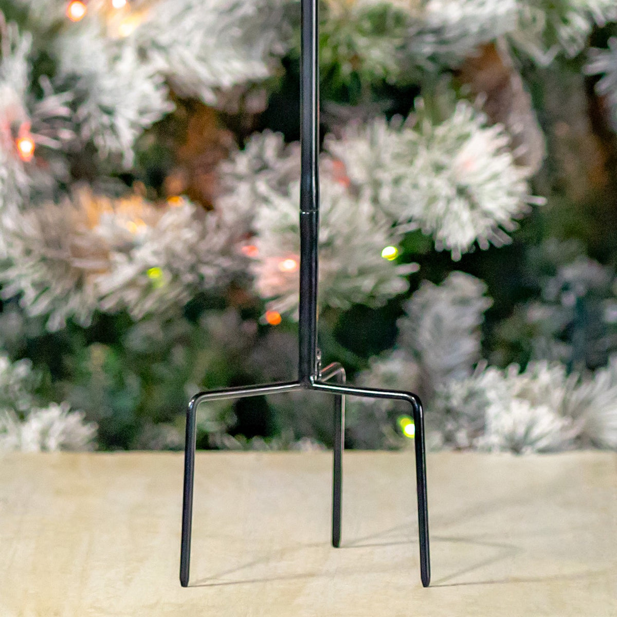 Close-up of the dark metal stake ending in two curved prongs on a pale floor.