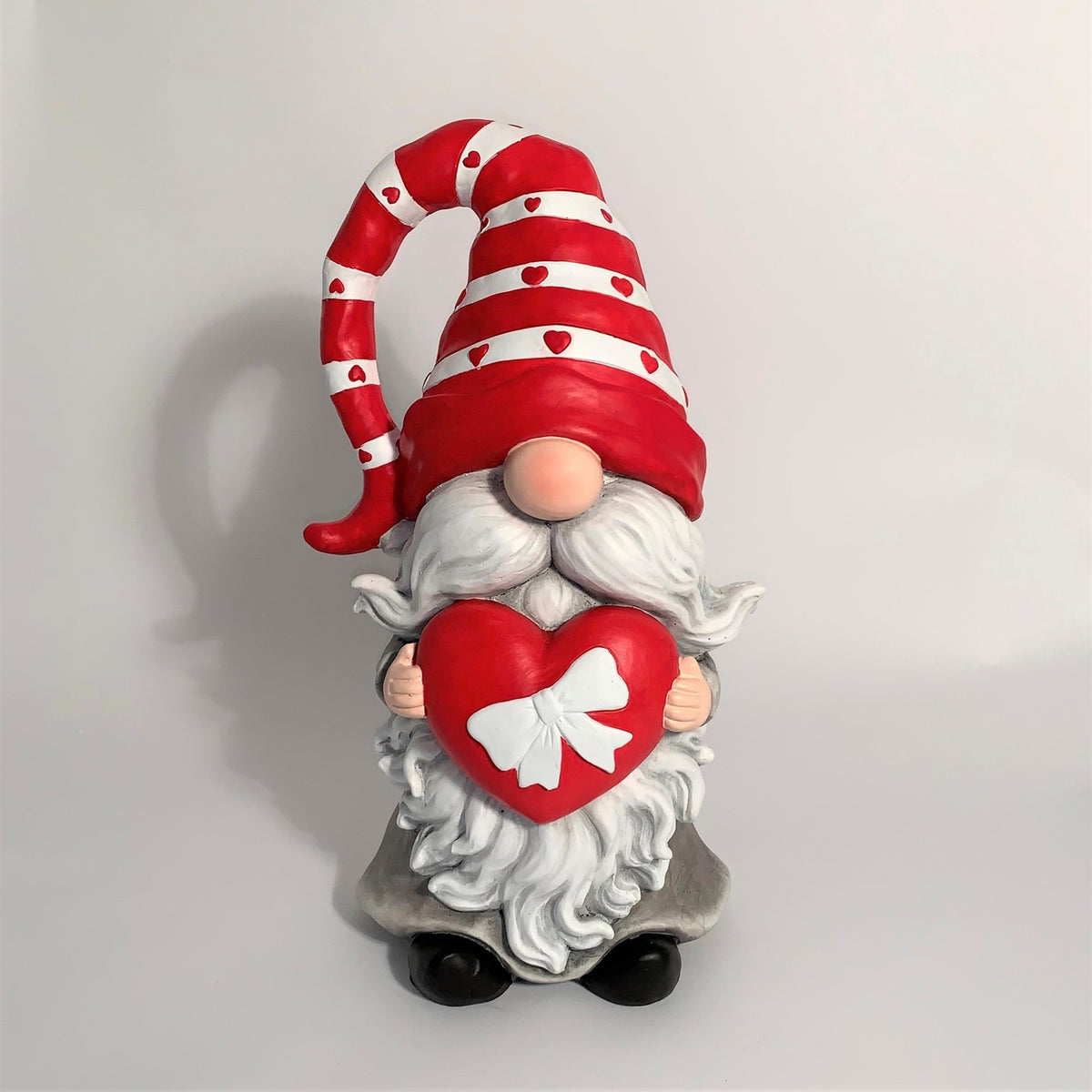 Front view of a Valentine gnome holding a red heart against a plain wall