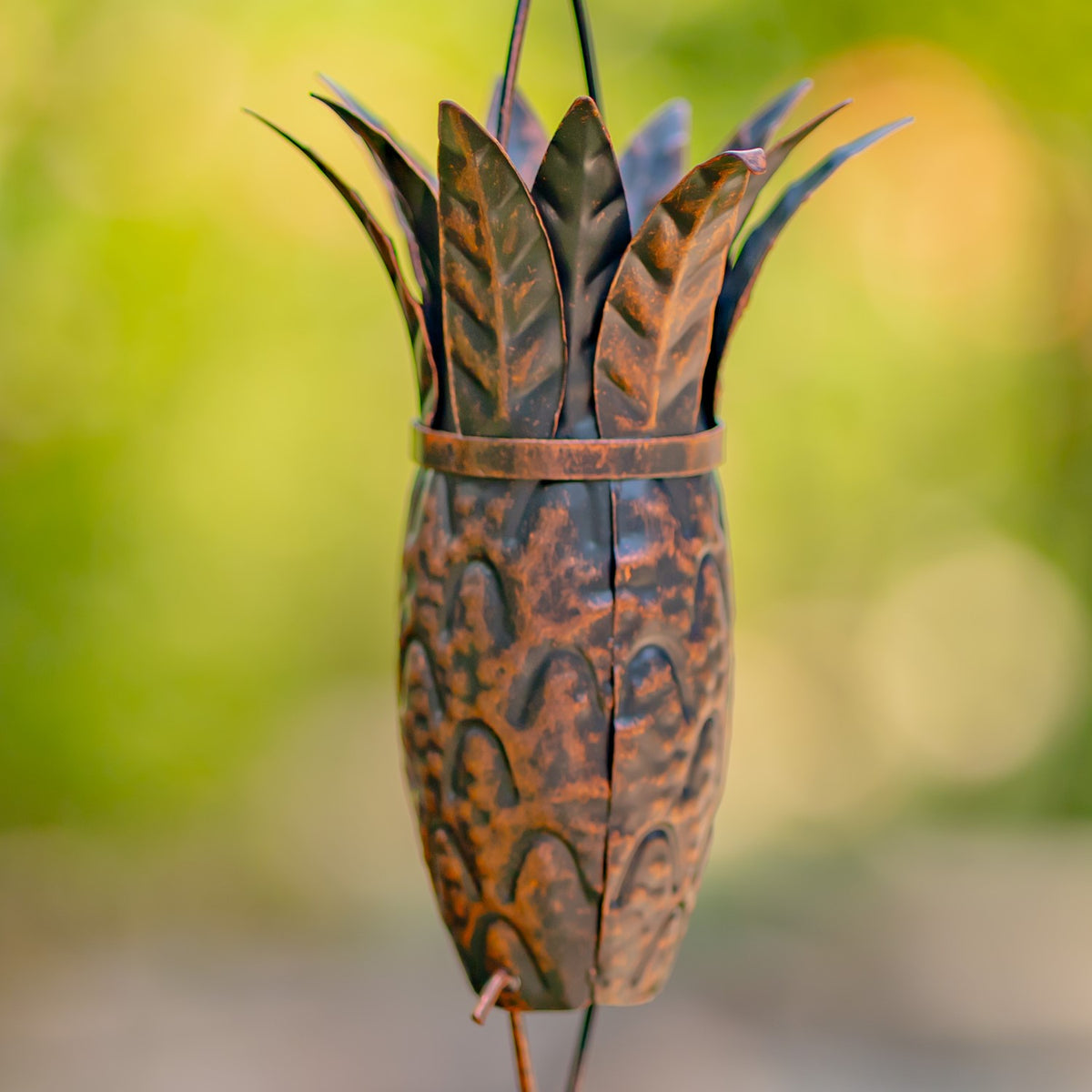 Detailed close-up of the distressed bronze finish on a pineapple-shaped rain chain link