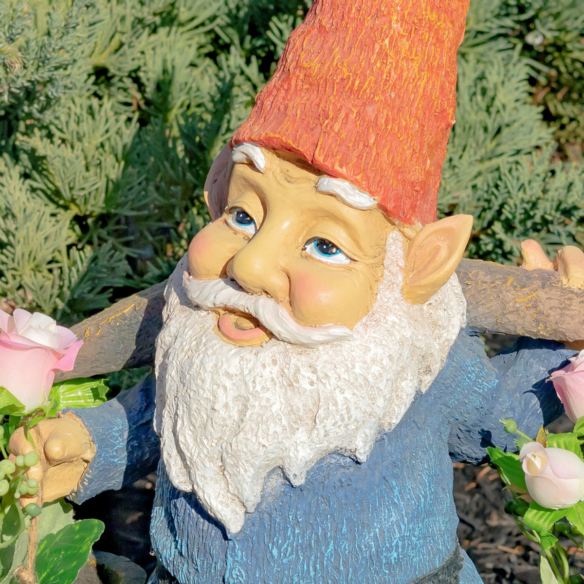 Close view of the garden gnome’s orange hat, blue eyes, white beard and flower-holding hands.