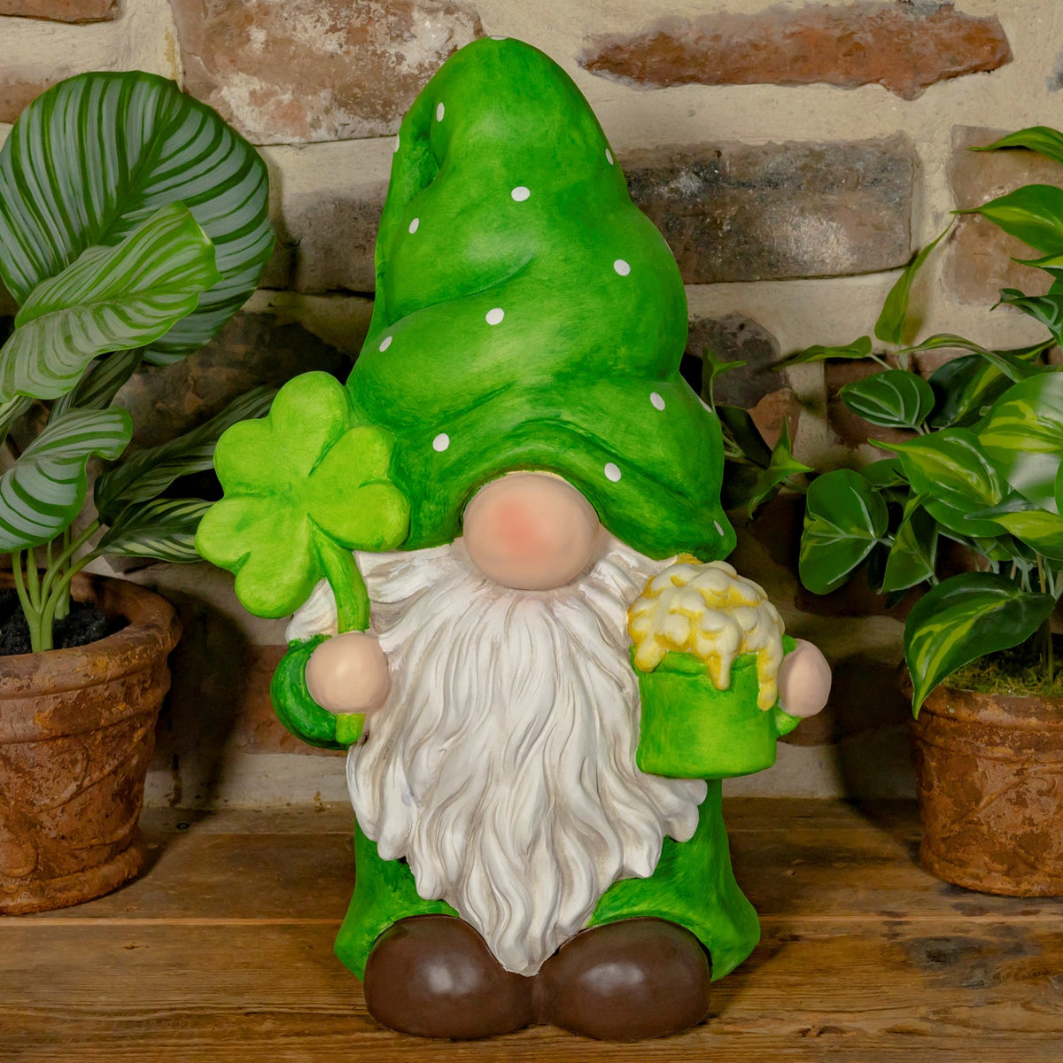 Green-hatted garden gnome with a white beard holds a shamrock and a small frothy mug.