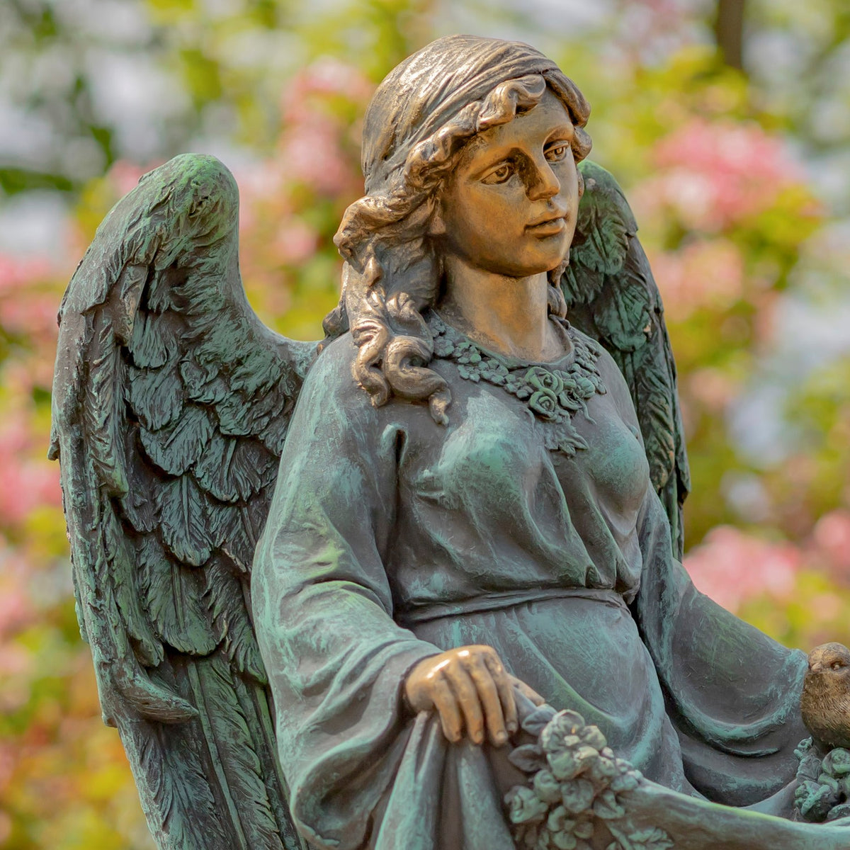 Angel statue viewed from the other side, showing her curled hair, feathered wing and gathered dress.