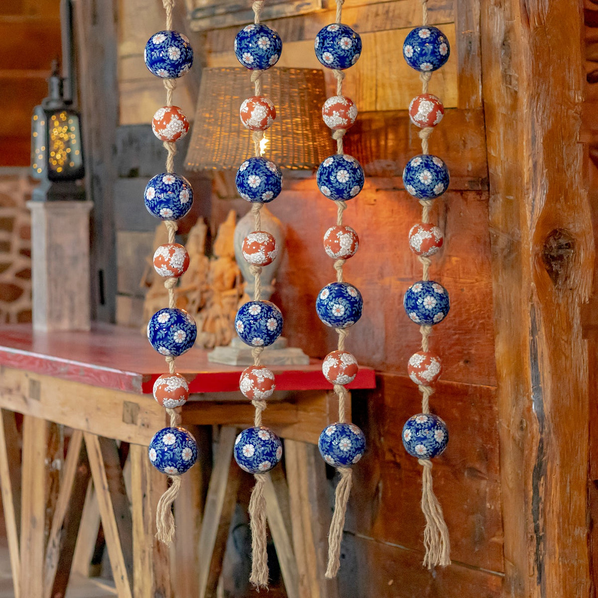 Four strands of blue and burnt-orange patterned porcelain balls hang against a rustic wood interior.