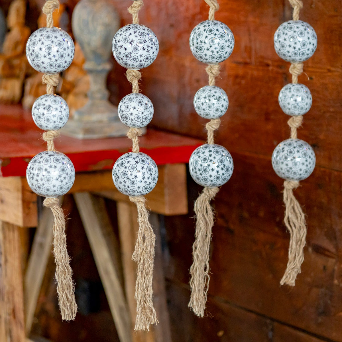 Several strands of patterned white ceramic balls hang against a warm wooden background.