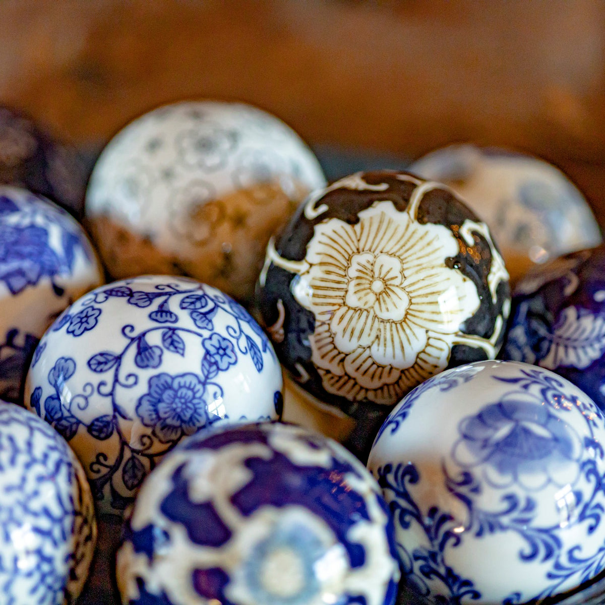 Assorted ceramic balls with blue-and-white floral patterns, nestled together with one dark floral ball near the center.
