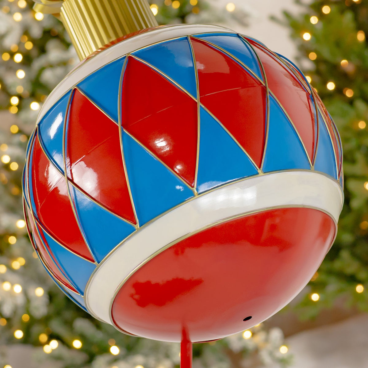 Close-up of a glossy red and blue ornament with gold diamond outlines and a wide white band.