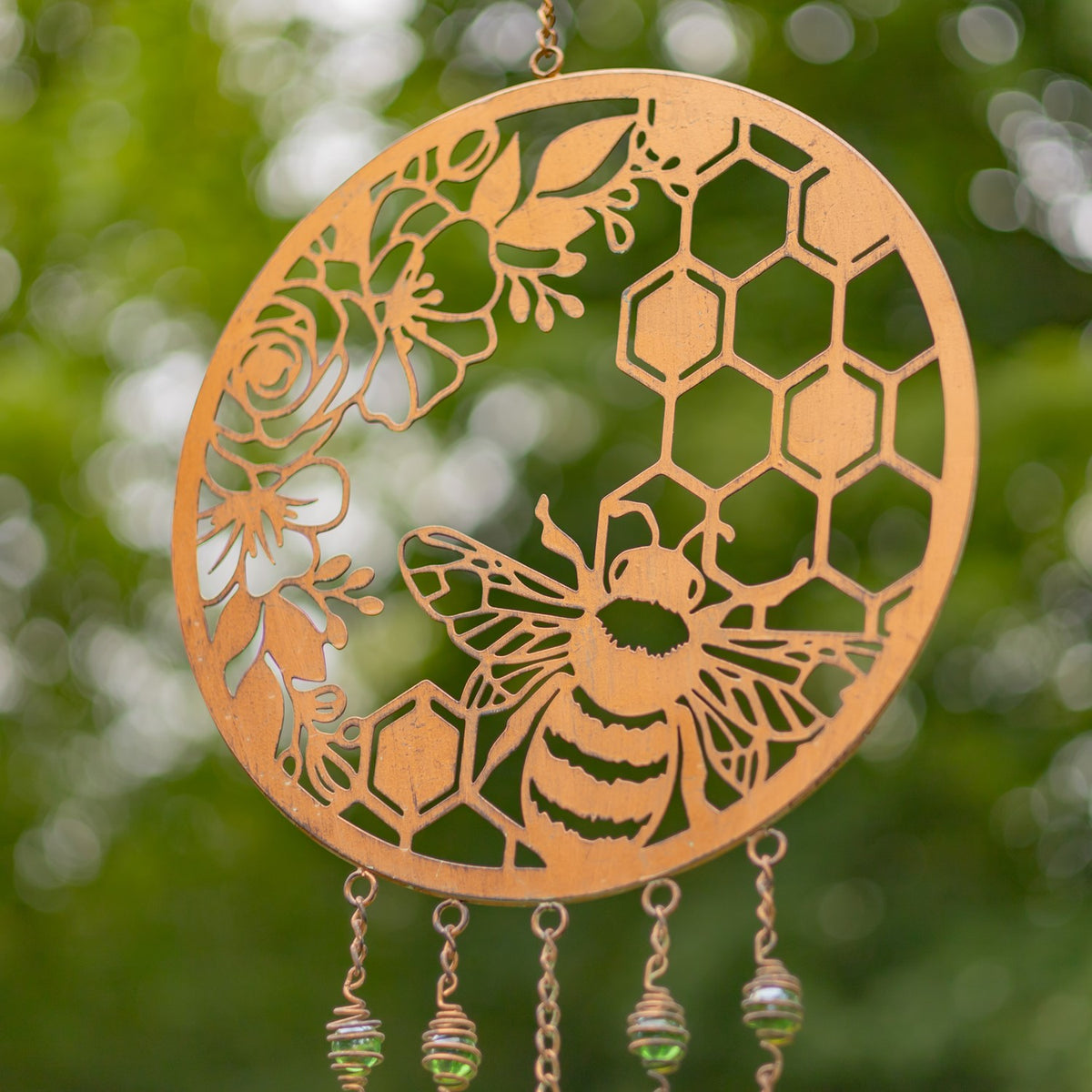 Close view of a copper-finish wind chime with a honeybee and honeycomb cutouts