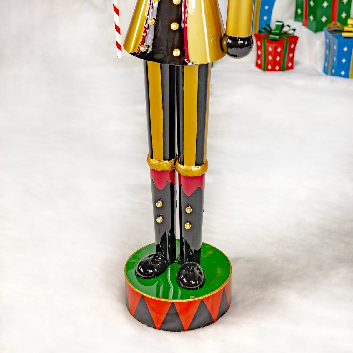 Close-up of the nutcracker’s black and gold legs, glossy shoes, and green circus-style base.
