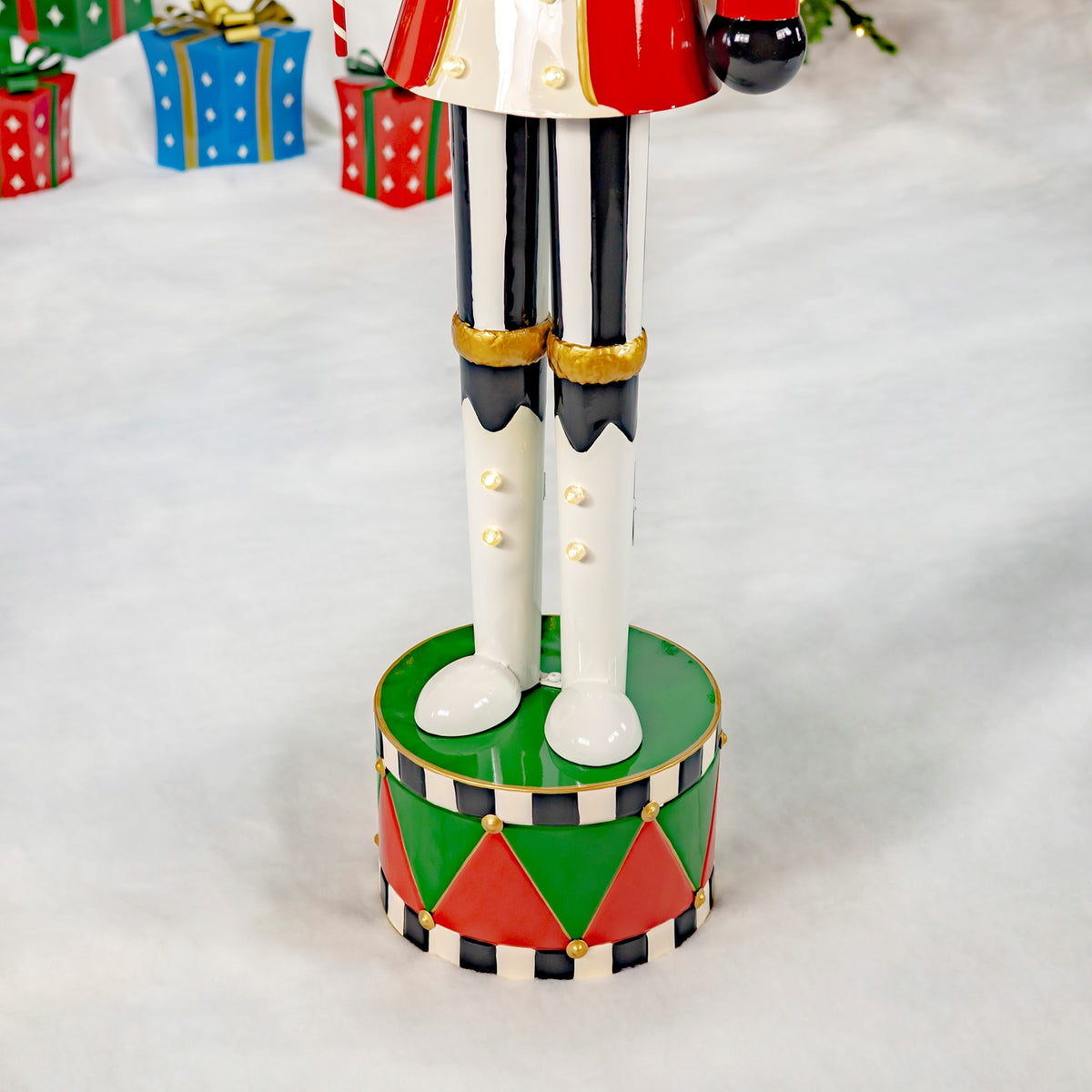 Close-up of the nutcracker’s white boots standing on a red, green, and black drum-shaped base.