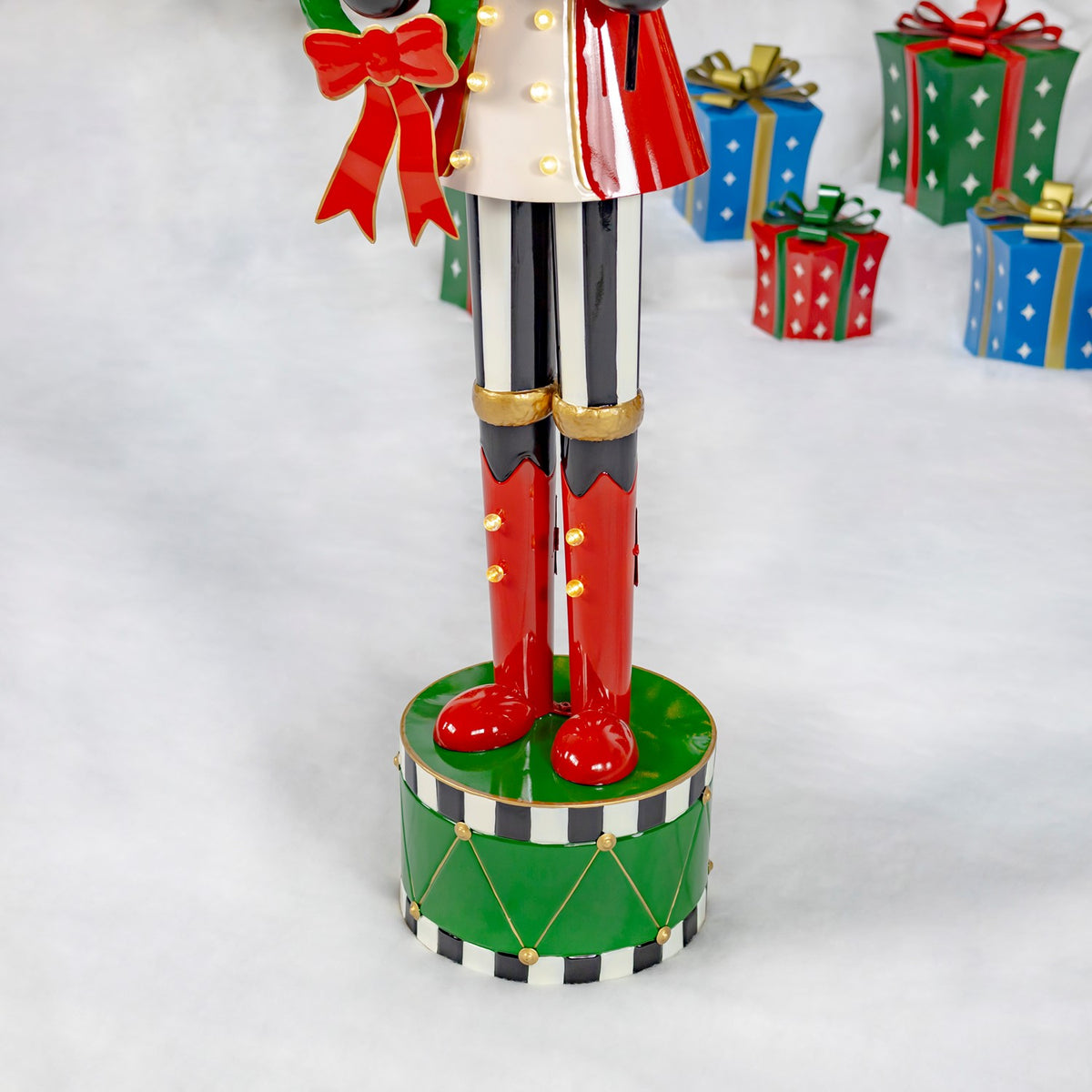 Red boots and striped legs stand on a green drum-shaped base with gold accents.