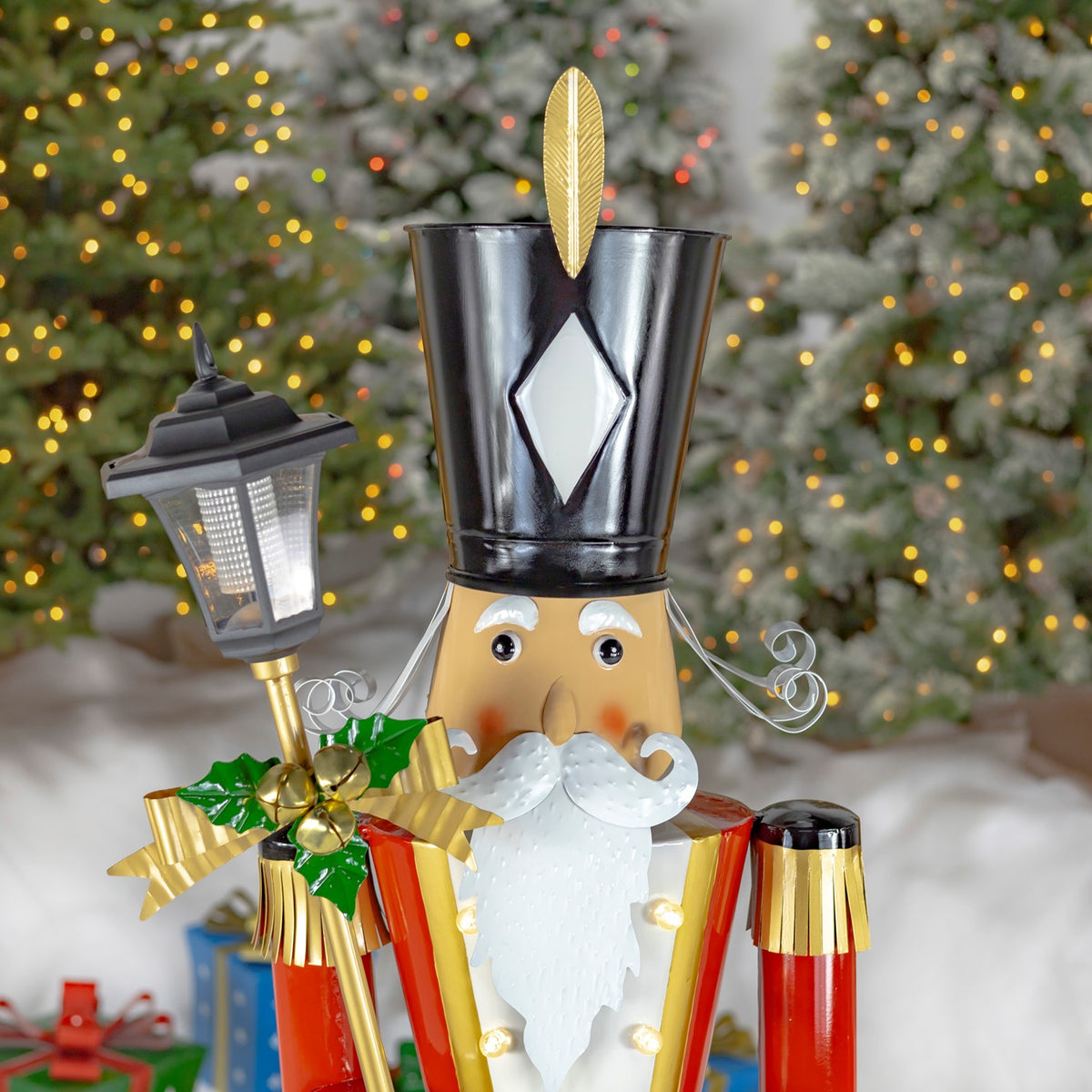 Close view of a mustached nutcracker holding a lantern, with a decorated tree behind him.