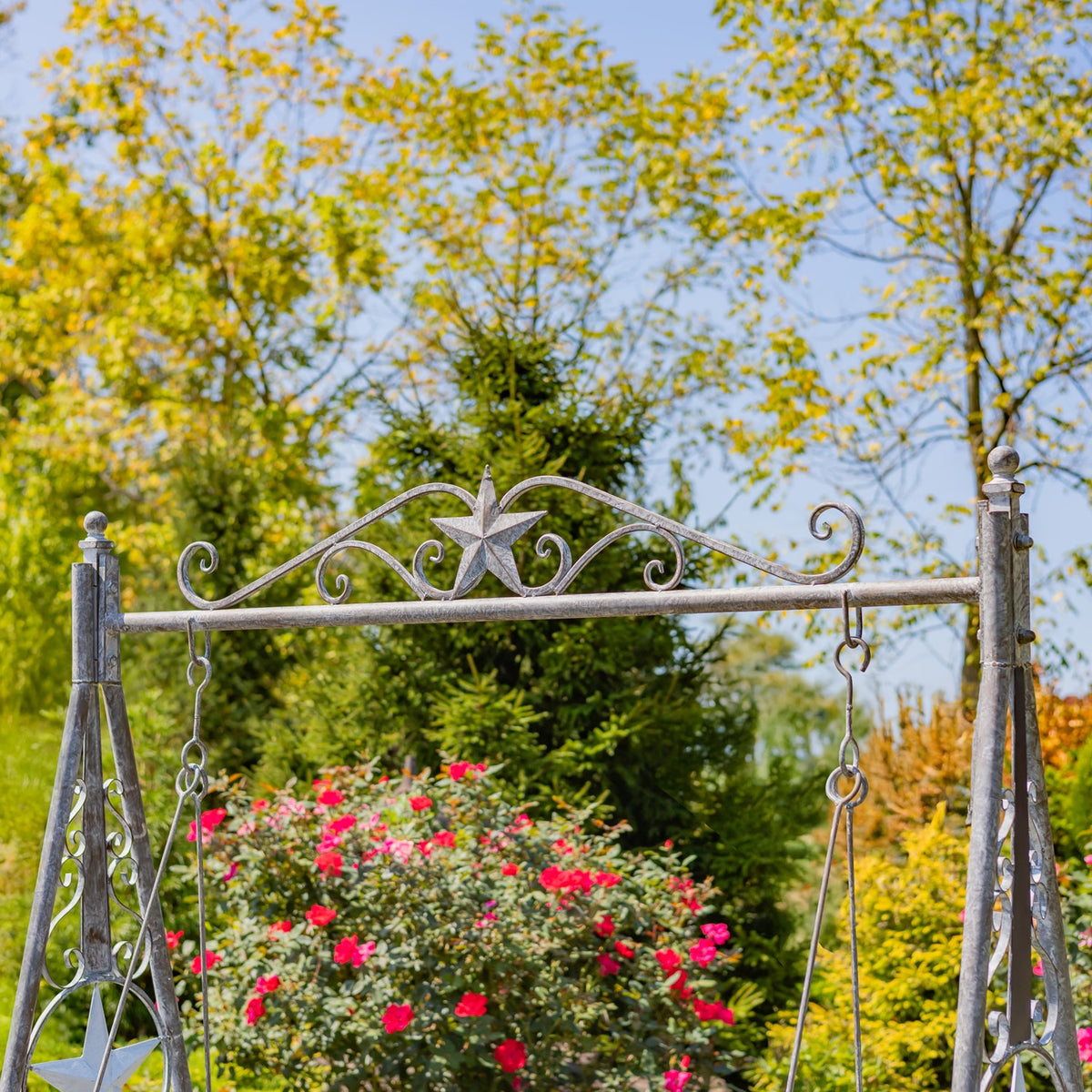 Upper iron swing frame with decorative star against a garden backdrop