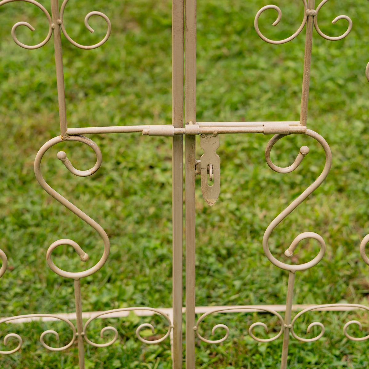 Close-up of the small metal latch on the decorative iron garden gate