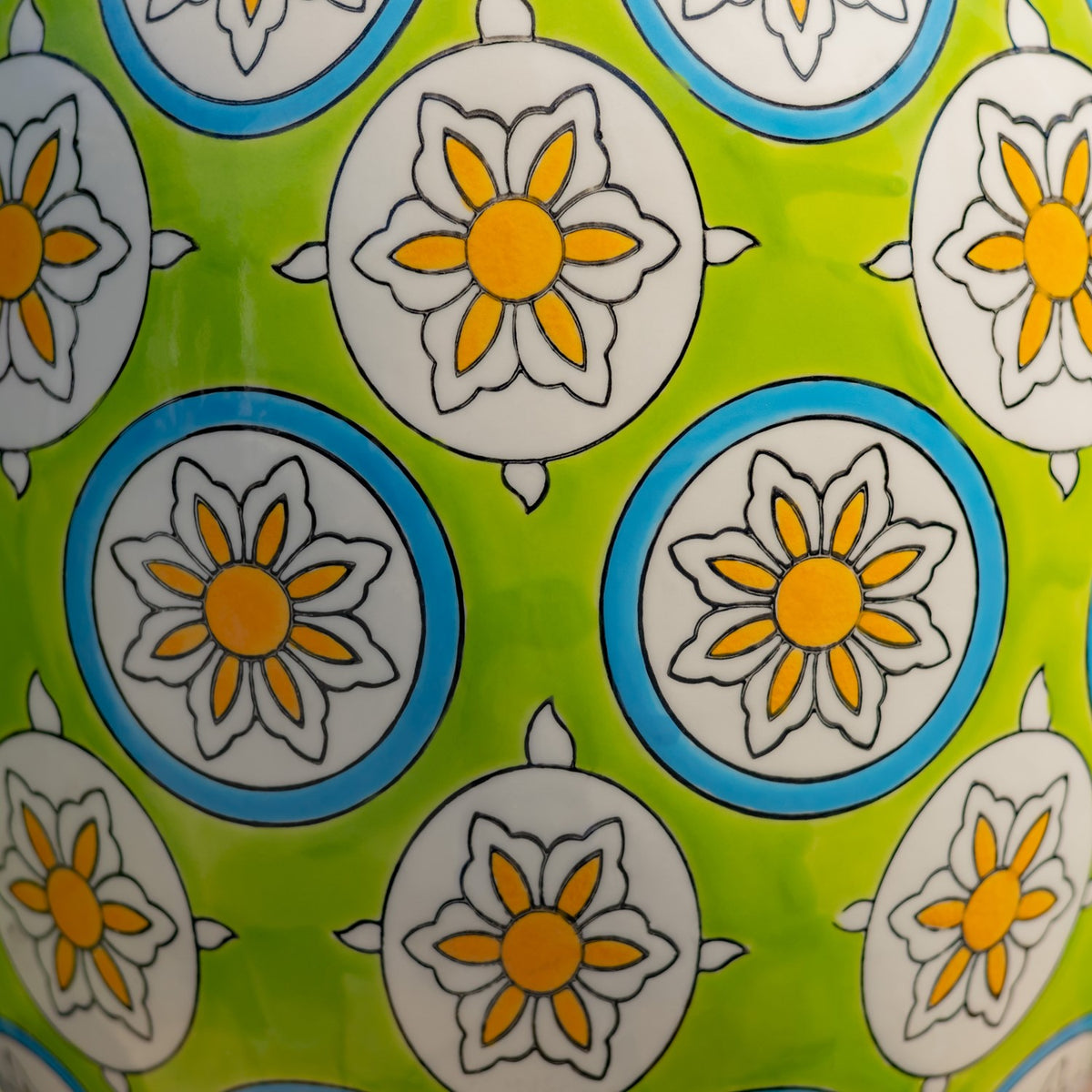 Close-up of a glossy green surface with repeating white and blue circles, each centered with an orange flower.