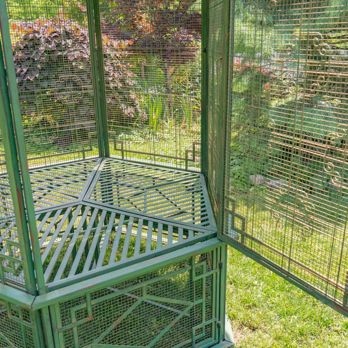 Inside view of a slatted metal floor and fine mesh walls meeting at a corner.