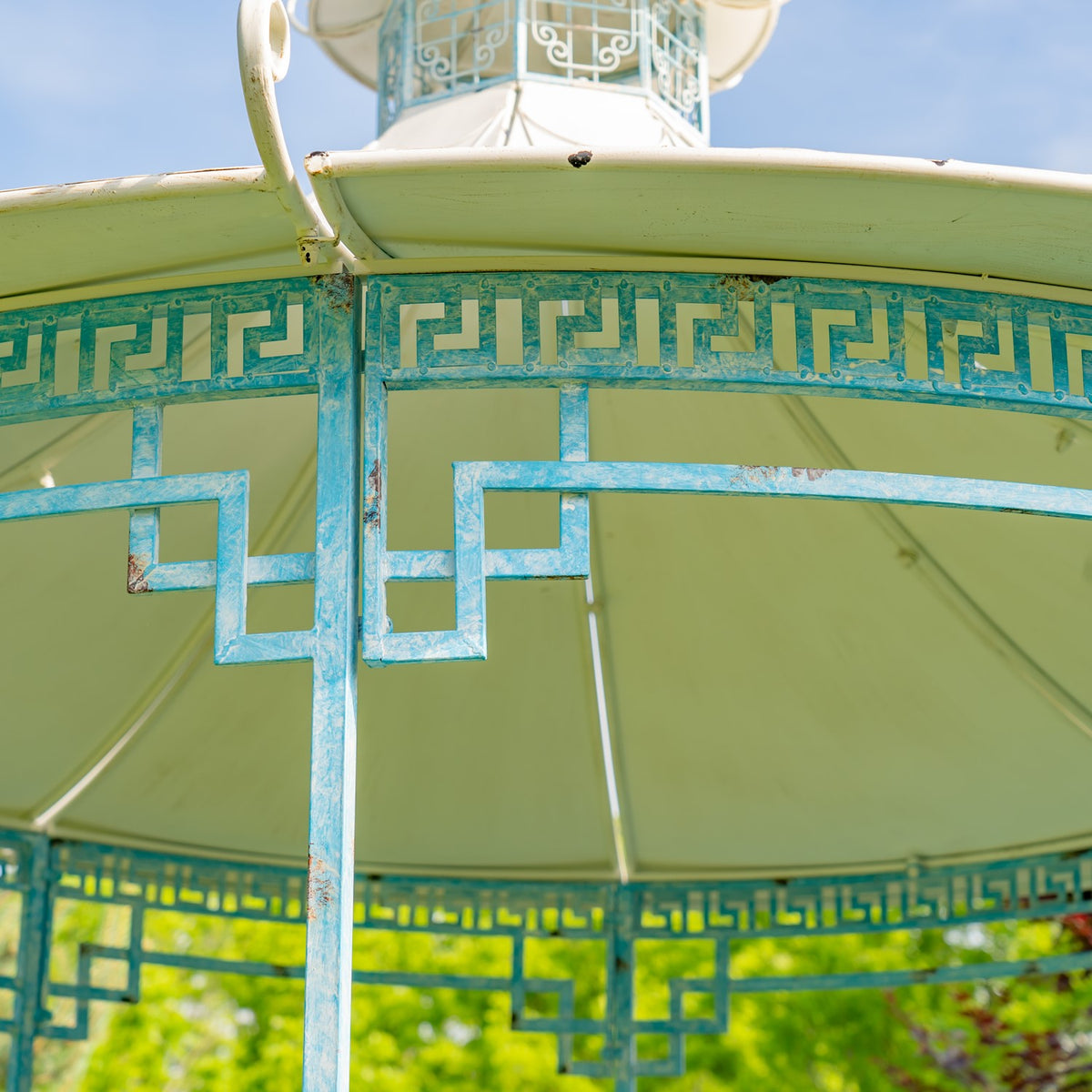 Close view of the gazebo’s pale canopy and ornate turquoise geometric trim and supports.