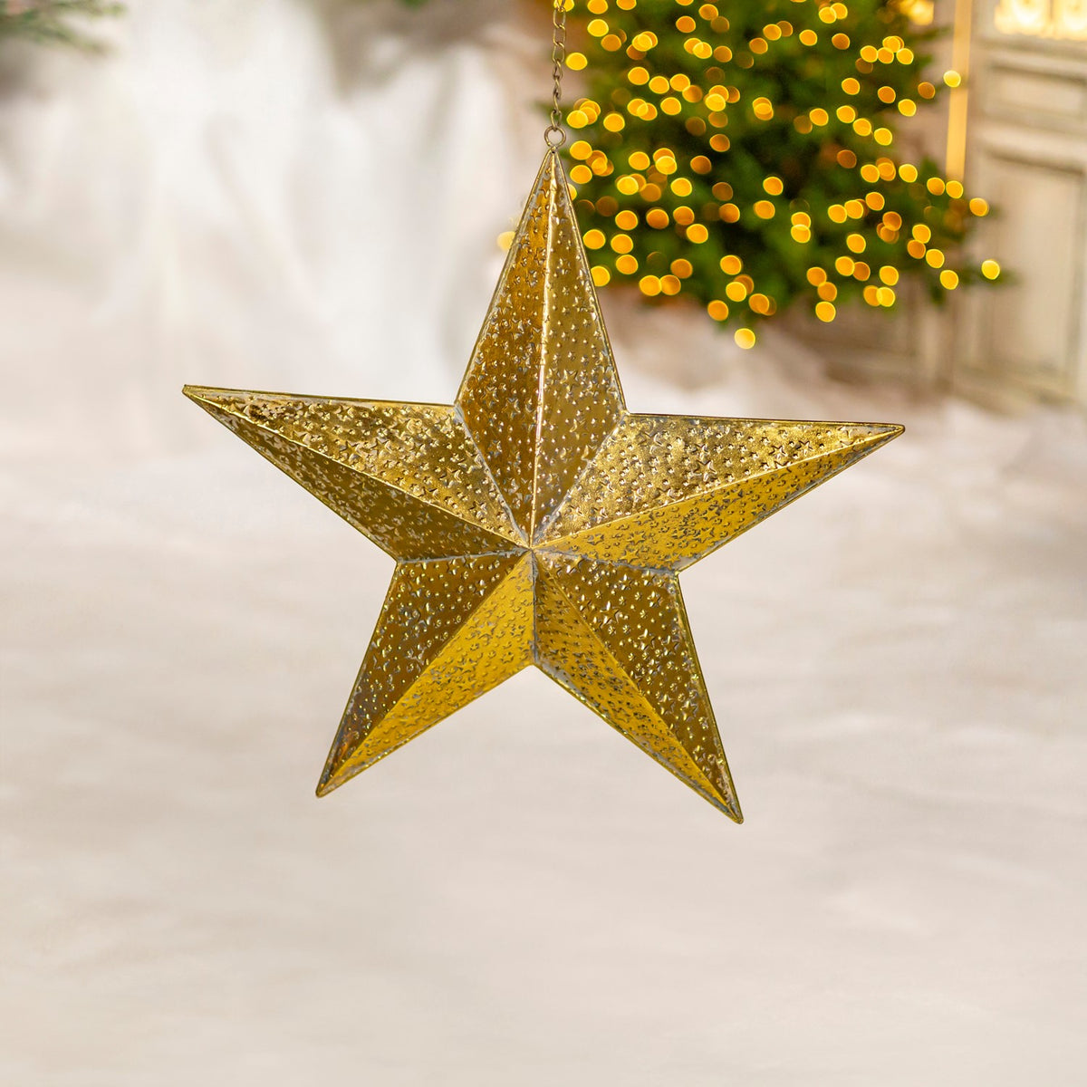 A faceted gold five-point star hangs against a softly lit holiday background.