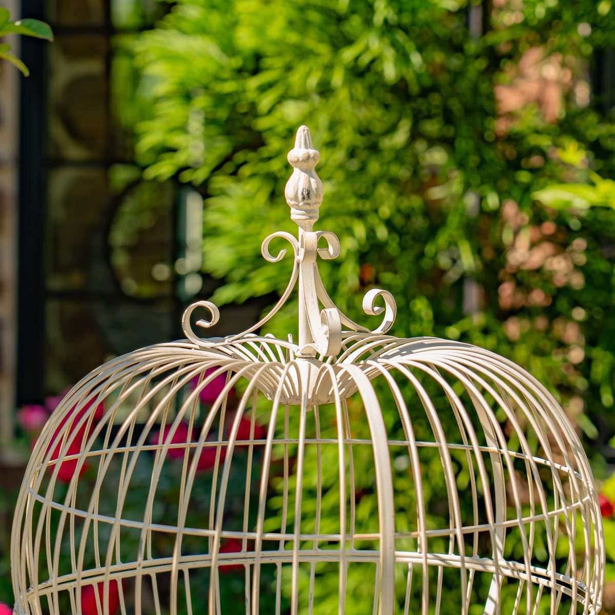 Close view of the wire stand’s curved top ornament and rounded cage bars.