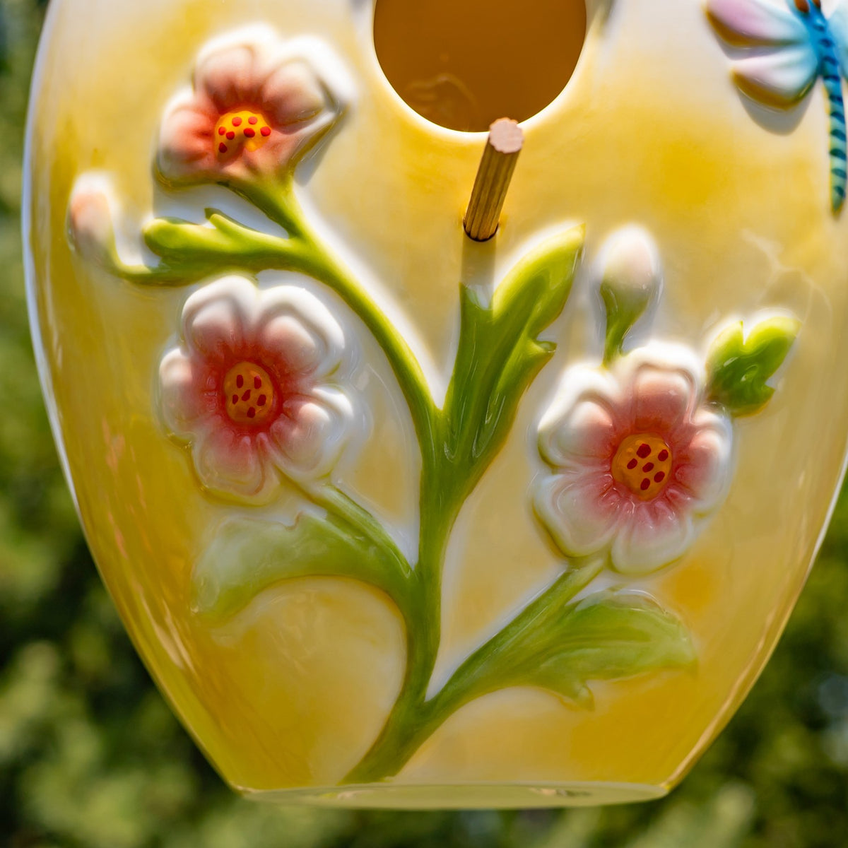 Close-up of raised pink flowers and green leaves around the birdhouse entrance.