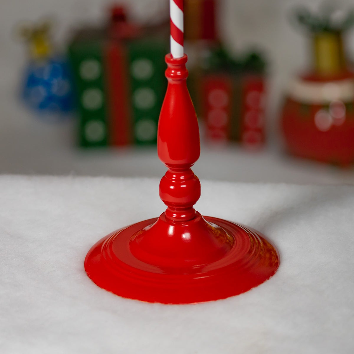 Close-up of the glossy red stand base and turned post on a snowy surface.