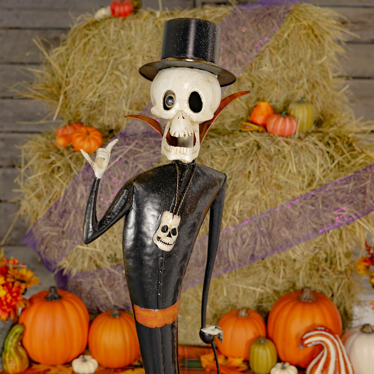 Close-up of a skeleton figurine in a black top hat with pumpkins behind it