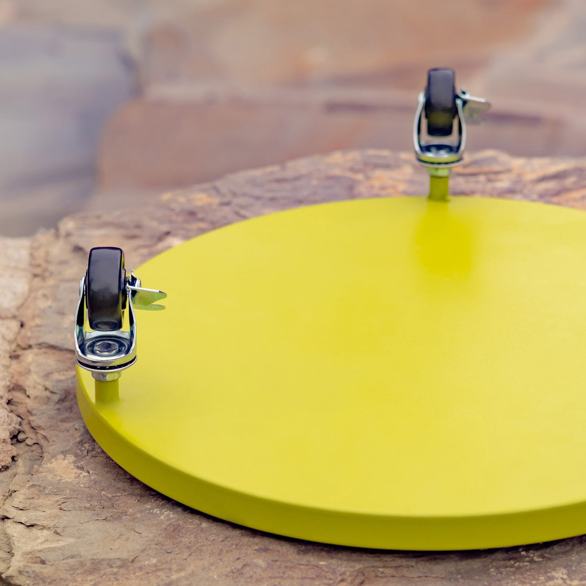 Close-up of a round yellow trolley base with two visible swivel casters underneath.