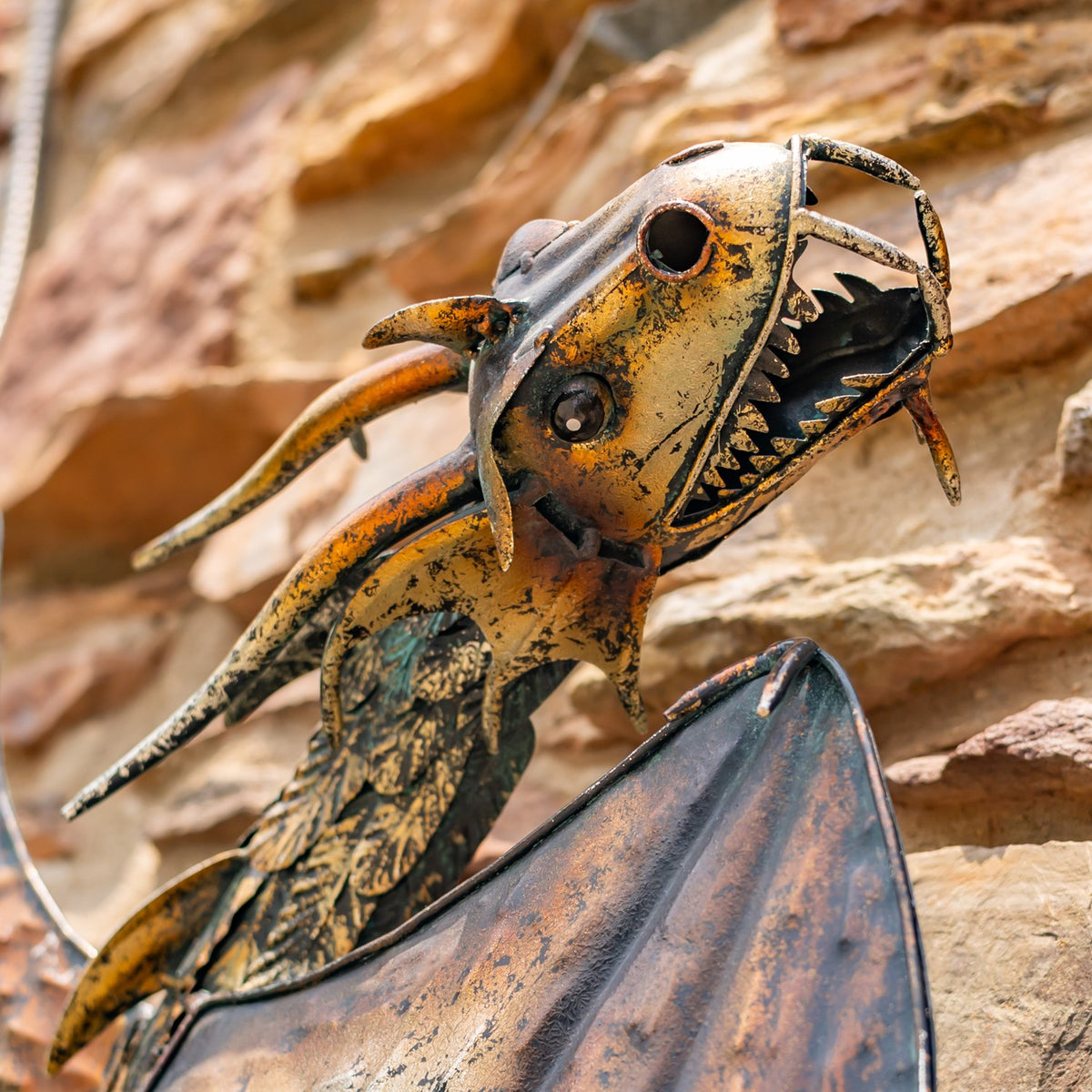 Close-up of the dragon’s open, tooth-lined mouth, textured head, and weathered bronze and black finish.
