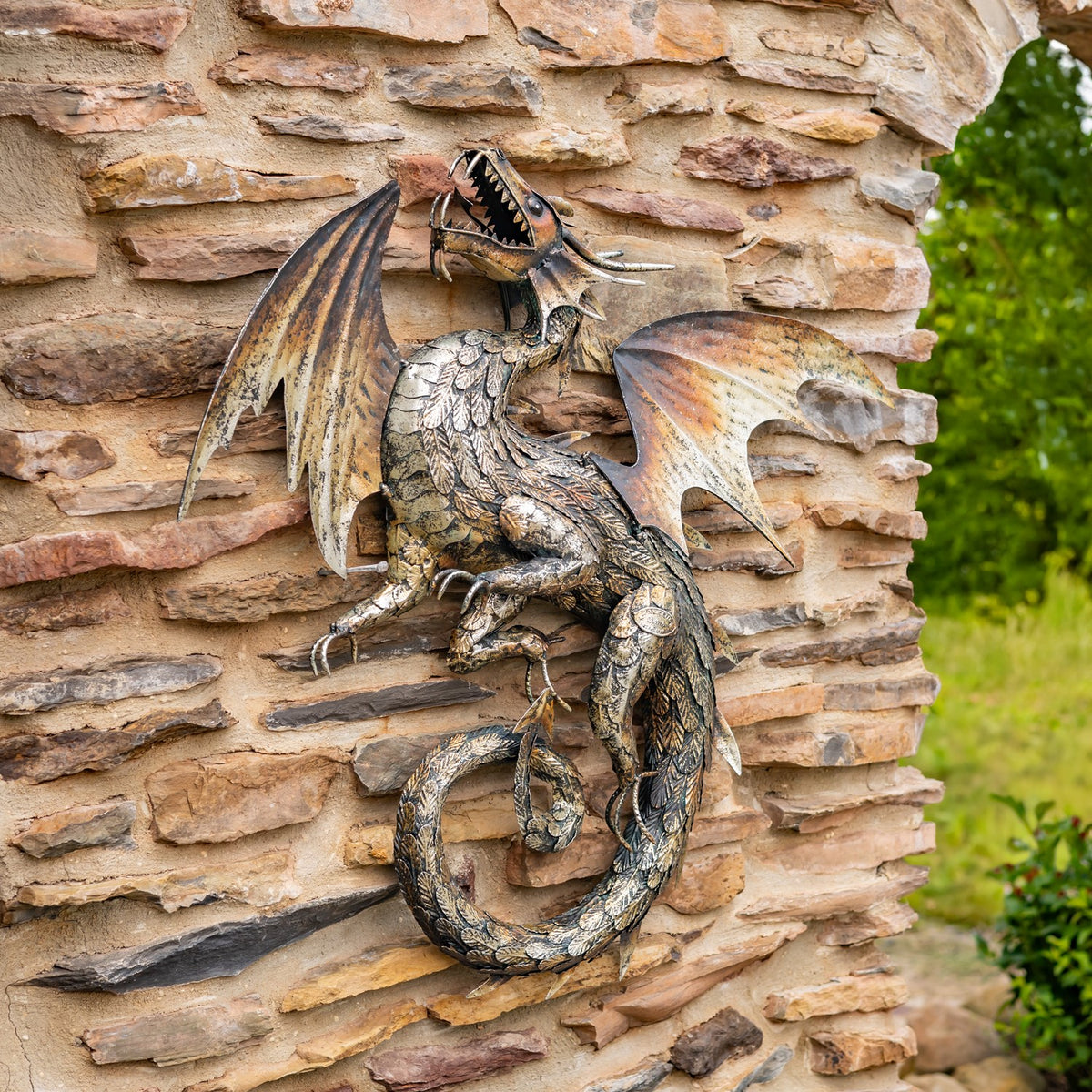 A bronze-toned dragon wall decoration with spread wings and a curled tail mounted on a stone wall.
