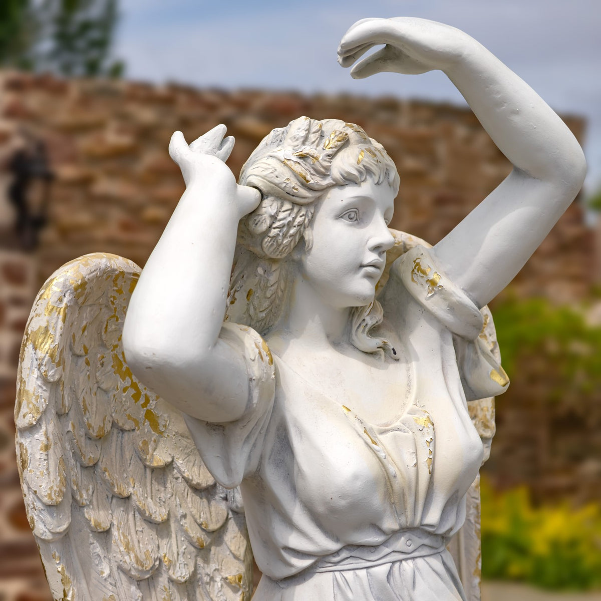 Close view of the angel’s raised arms, flowing hair, face and weathered wings.