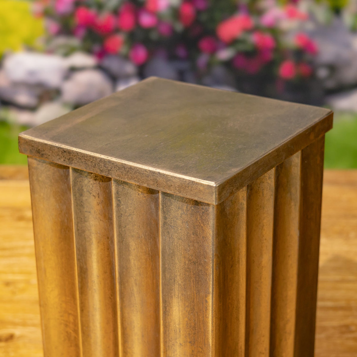 Close view of a pedestal’s square top and vertically fluted sides.