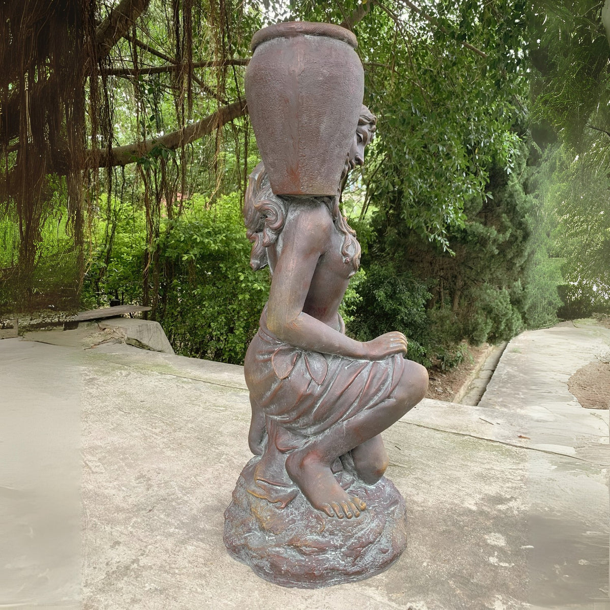 Side view of the kneeling statue, showing the urn above her shoulder and her bare feet on the sculpted base.
