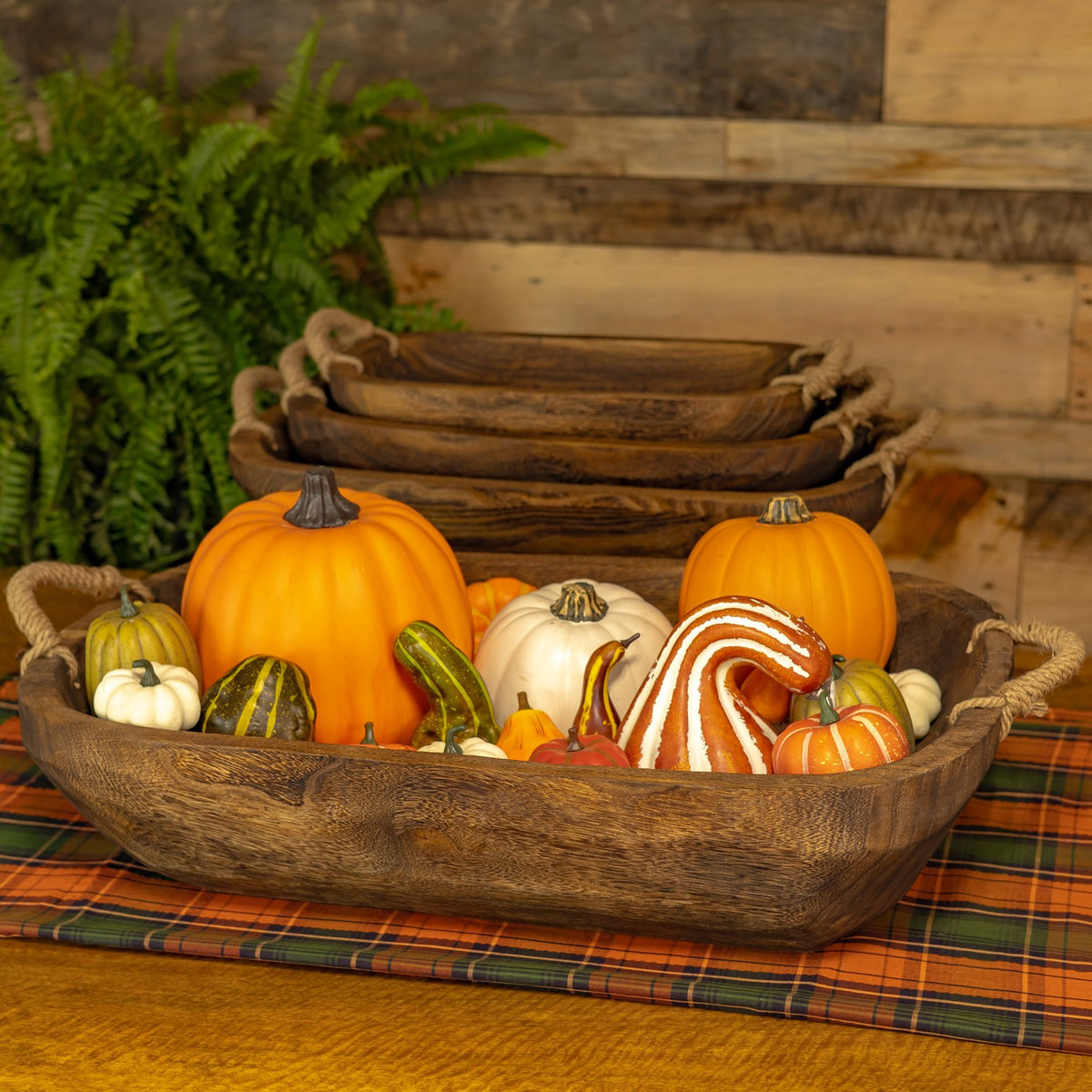A wooden tray filled with colorful pumpkins and gourds, with nested trays behind it.