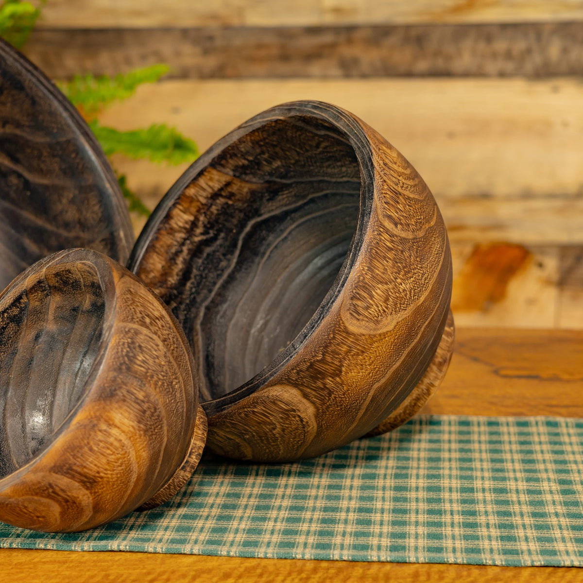 Close view of two round wooden planters showing their dark interiors and swirling grain.