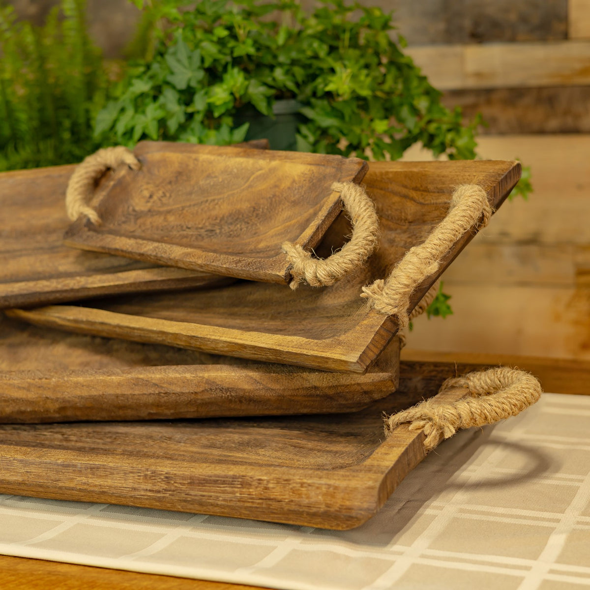 Angled view of stacked brown wooden trays with rope handles
